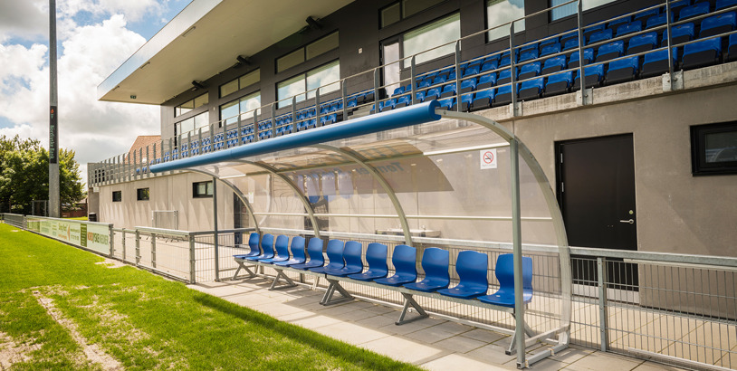 Ett avbytarbås med blå säten placerad på en fotbollsplan