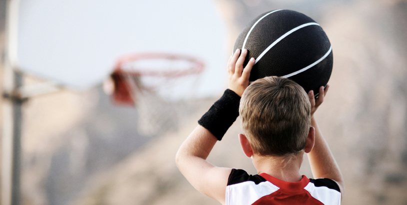 En kille i röd tröja som håller en svart basketboll